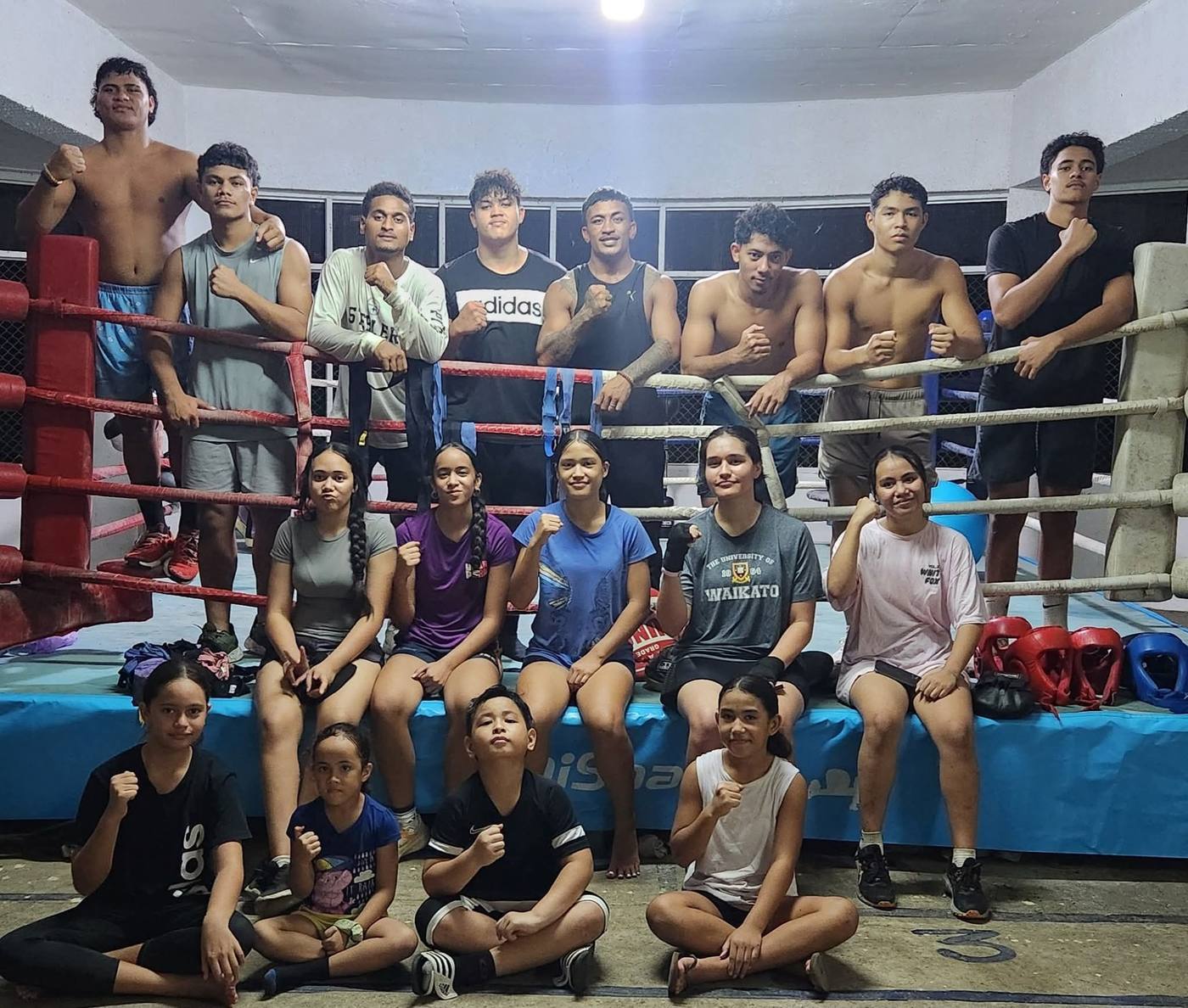 The SUBA squad, kids, youth and adults, posing with fists up around the ring